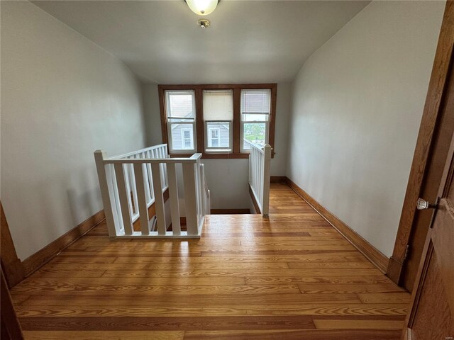 hall with lofted ceiling, baseboards, an upstairs landing, and wood finished floors