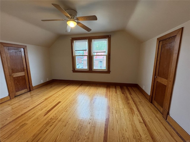 additional living space with vaulted ceiling, light wood finished floors, baseboards, and a ceiling fan