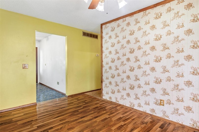 spare room featuring wood finished floors, a ceiling fan, and baseboards