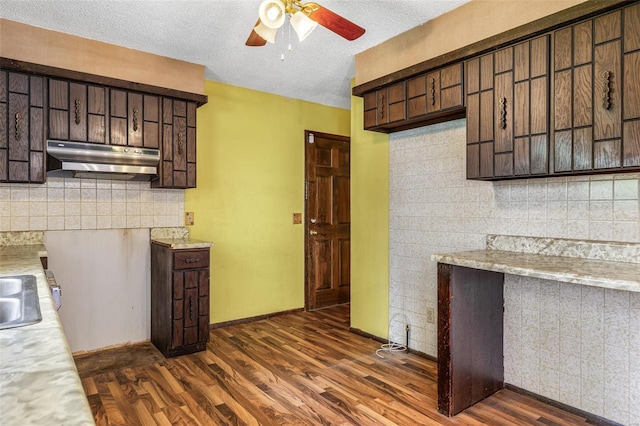 kitchen featuring ceiling fan, light countertops, under cabinet range hood, dark wood-style floors, and a textured ceiling