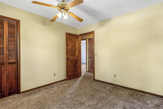 unfurnished bedroom with carpet flooring, a closet, baseboards, ceiling fan, and a textured ceiling