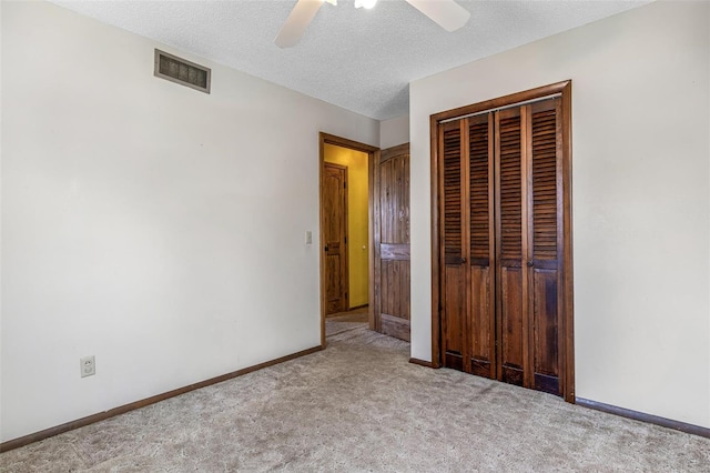 unfurnished bedroom featuring carpet, a closet, a textured ceiling, baseboards, and ceiling fan