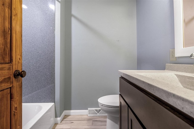 bathroom with vanity, toilet, a tub to relax in, baseboards, and wood finished floors