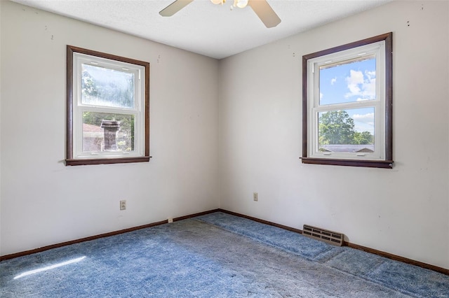 carpeted empty room with plenty of natural light, a ceiling fan, and baseboards