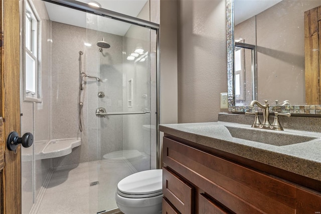 bathroom featuring toilet, a shower stall, vanity, and a textured wall