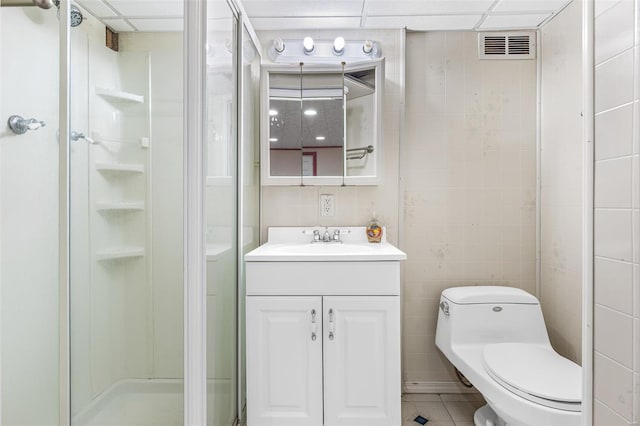 full bathroom with a stall shower, toilet, vanity, tile walls, and tile patterned flooring