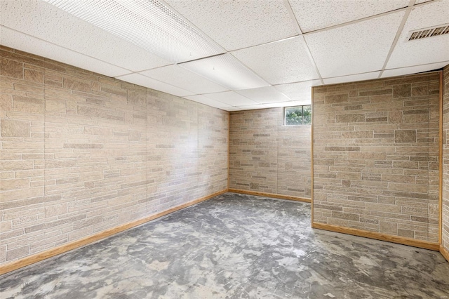 spare room with a paneled ceiling, unfinished concrete flooring, and baseboards