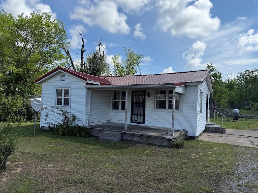 view of front of property featuring a porch, metal roof, and a front lawn