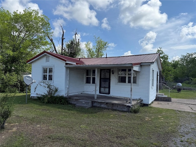 view of front of property featuring a porch, metal roof, and a front lawn