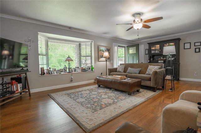 living room featuring ceiling fan, crown molding, wood finished floors, and baseboards