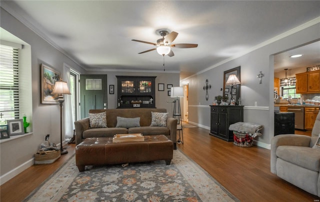 living room with ceiling fan, wood finished floors, crown molding, and baseboards
