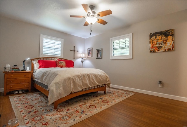 bedroom featuring baseboards, multiple windows, and wood finished floors