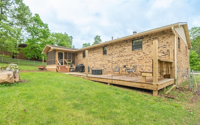rear view of house featuring a sunroom, a deck, central AC, and brick siding