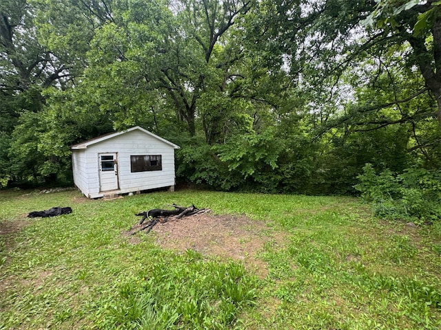 view of grassy yard with an outbuilding, a storage unit, and a view of trees
