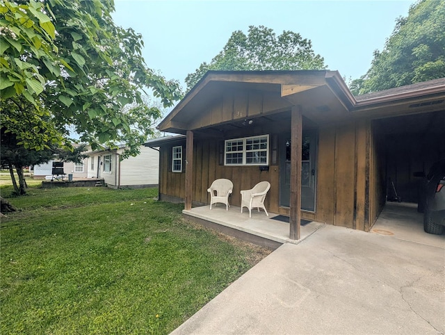 back of house featuring board and batten siding, a lawn, and covered porch