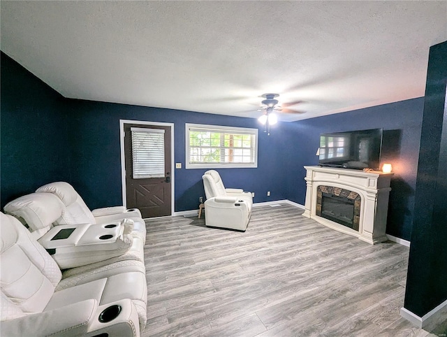 living room with a ceiling fan, a fireplace, wood finished floors, and baseboards