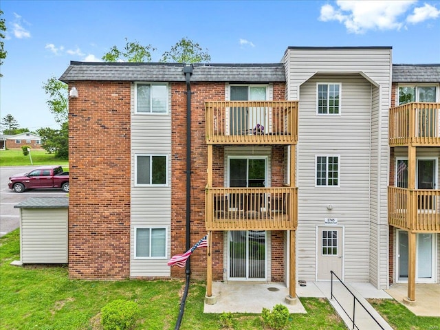back of property featuring brick siding, a patio, and a lawn