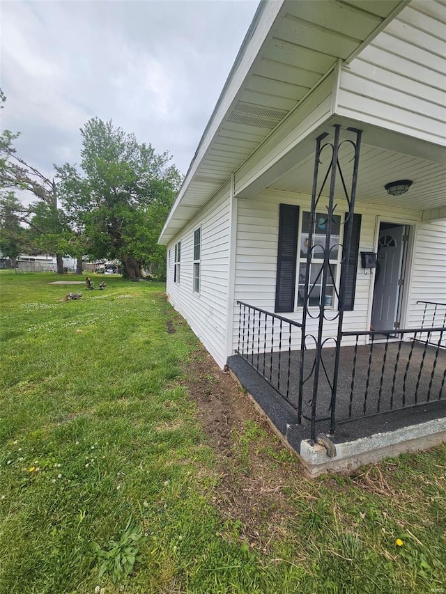 view of side of property with a lawn and covered porch