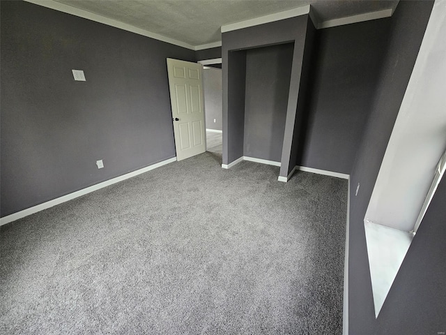 unfurnished bedroom featuring carpet flooring, a closet, baseboards, a textured ceiling, and ornamental molding