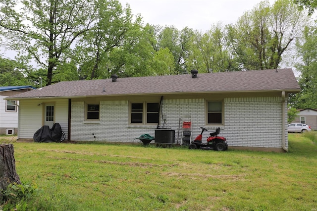 back of house featuring central AC unit, brick siding, and a lawn