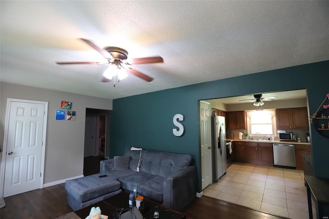 living area featuring a ceiling fan, light wood-type flooring, and baseboards