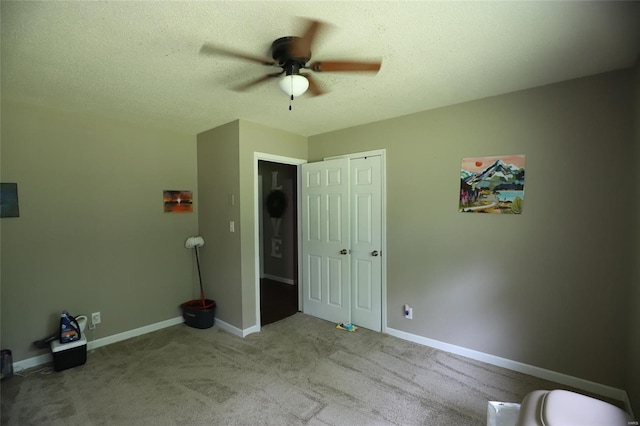 unfurnished bedroom with carpet, baseboards, a ceiling fan, a textured ceiling, and a closet