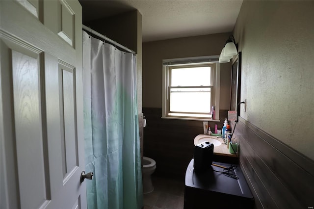 full bathroom with toilet, wainscoting, vanity, a textured ceiling, and curtained shower