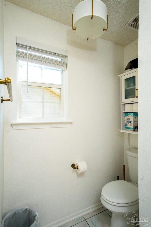 bathroom featuring toilet, tile patterned floors, and a textured ceiling