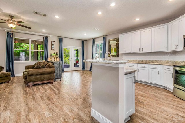 kitchen featuring white cabinets, stainless steel range, light wood-type flooring, and ceiling fan