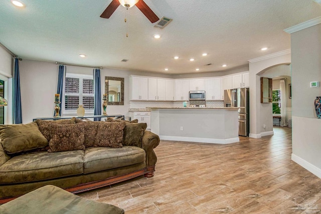 living room featuring a textured ceiling, crown molding, and ceiling fan