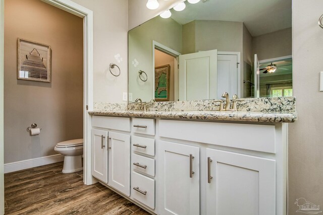 bathroom with hardwood / wood-style flooring, toilet, ceiling fan, and dual bowl vanity