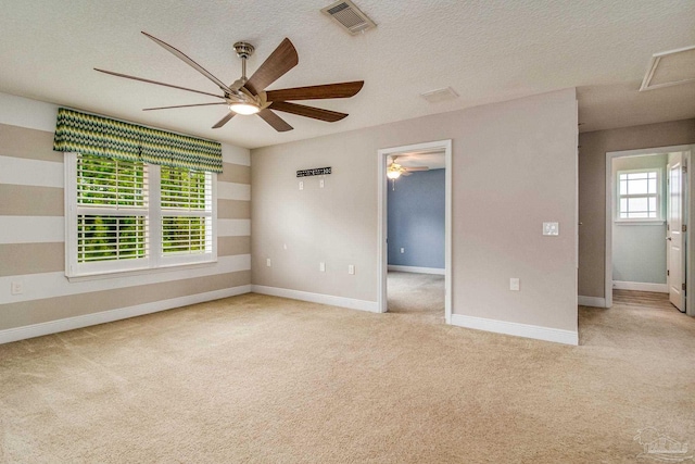 carpeted spare room featuring a textured ceiling and ceiling fan