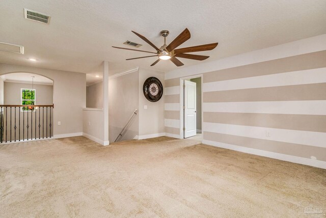 carpeted spare room featuring a textured ceiling and ceiling fan