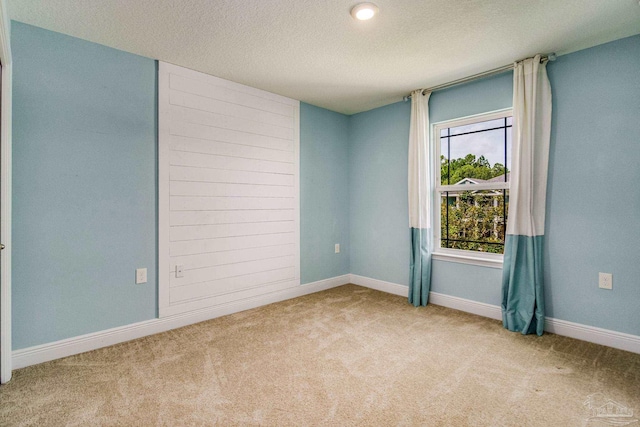 empty room with light carpet and a textured ceiling