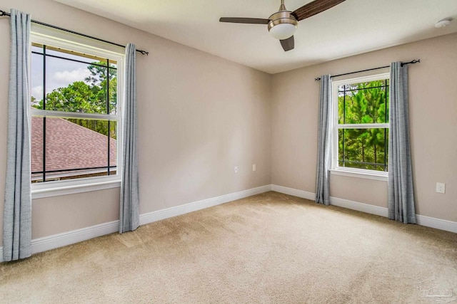 empty room with ceiling fan, light colored carpet, and plenty of natural light