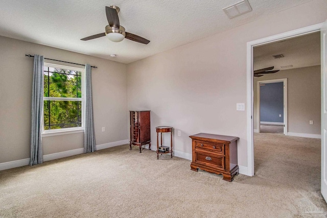 unfurnished room with a textured ceiling, light colored carpet, and ceiling fan