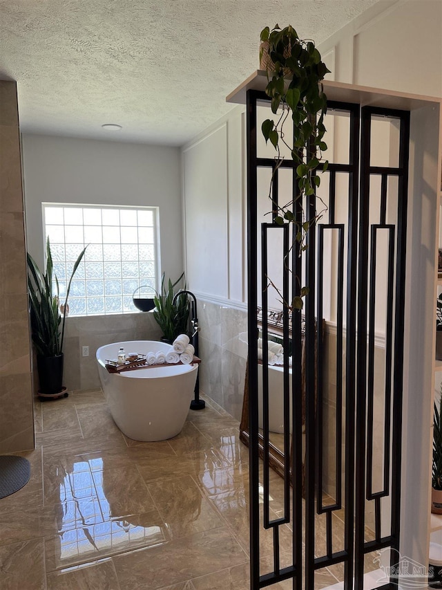 bathroom with tile walls, a washtub, and a textured ceiling