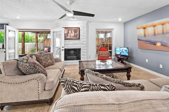 living room featuring a fireplace, ceiling fan, and a textured ceiling