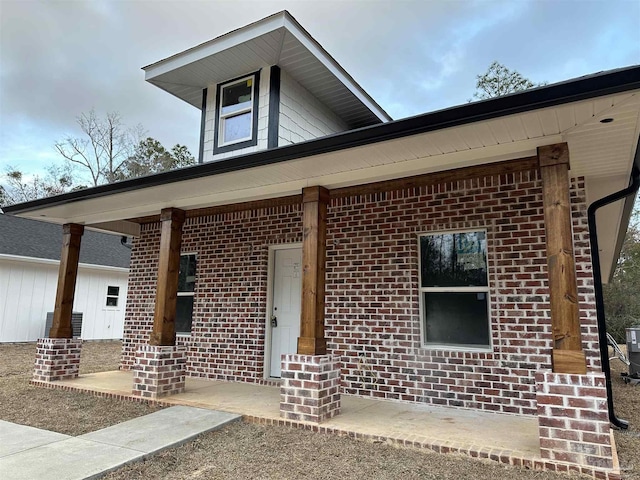 view of front of house with a porch and brick siding