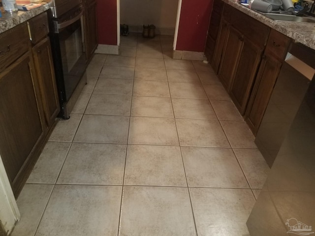 kitchen featuring light tile patterned flooring, stove, and sink