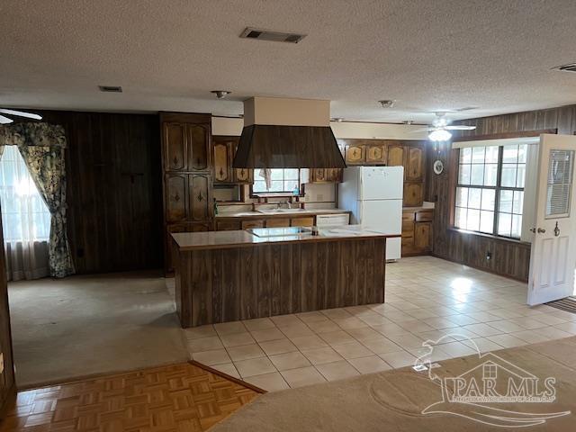 kitchen with white refrigerator, dark brown cabinets, wooden walls, and ceiling fan