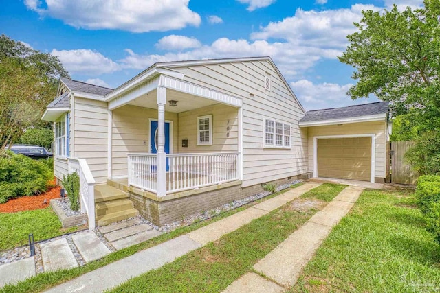 bungalow-style house with covered porch, a front yard, and a garage