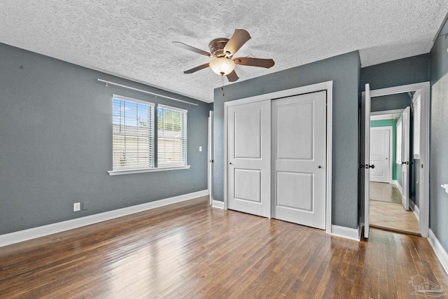 unfurnished bedroom featuring a closet, ceiling fan, dark hardwood / wood-style floors, and a textured ceiling