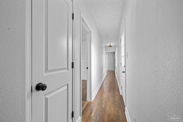 hallway with a textured ceiling and dark hardwood / wood-style flooring