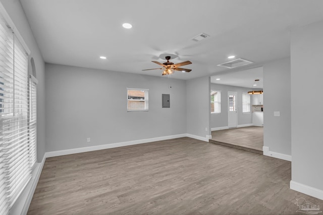 unfurnished room featuring electric panel, visible vents, baseboards, and wood finished floors