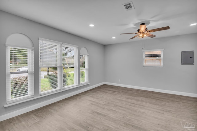 empty room featuring light wood finished floors, visible vents, electric panel, and baseboards