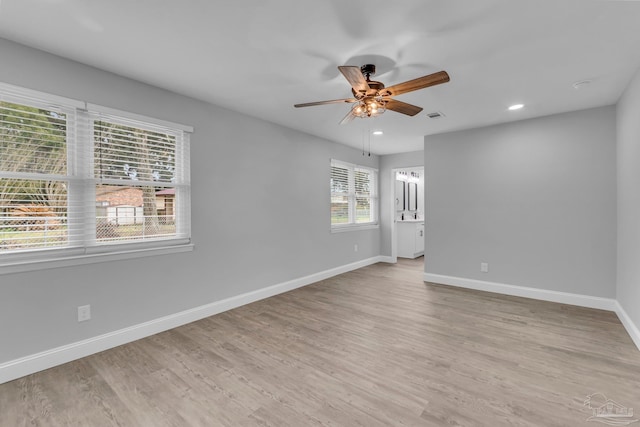 spare room with ceiling fan, light wood finished floors, visible vents, and baseboards