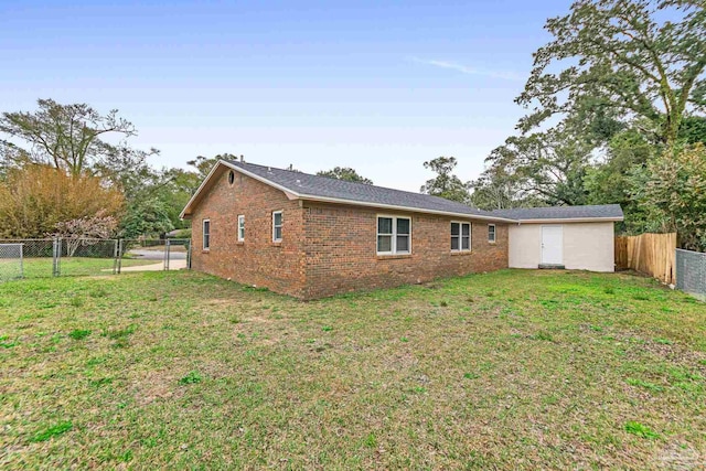 back of property featuring a yard, brick siding, a fenced backyard, and a gate