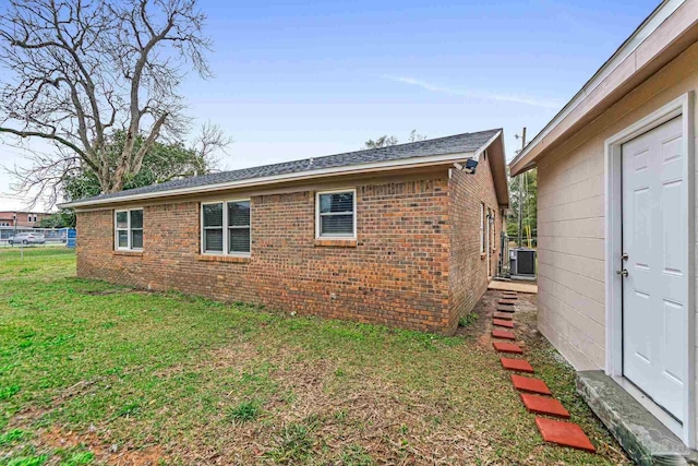 view of side of property featuring a yard, cooling unit, and brick siding