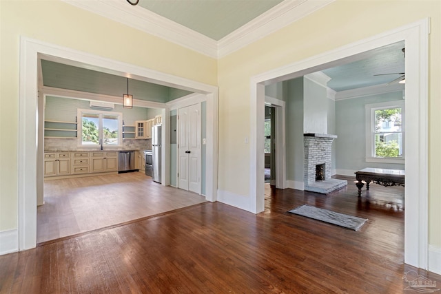 interior space with sink, ceiling fan, a fireplace, ornamental molding, and dark hardwood / wood-style flooring